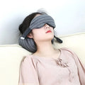 Reclining model wearing a gray padded eye and neck pillow