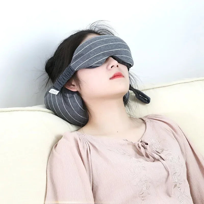 Reclining model wearing a gray padded eye and neck pillow