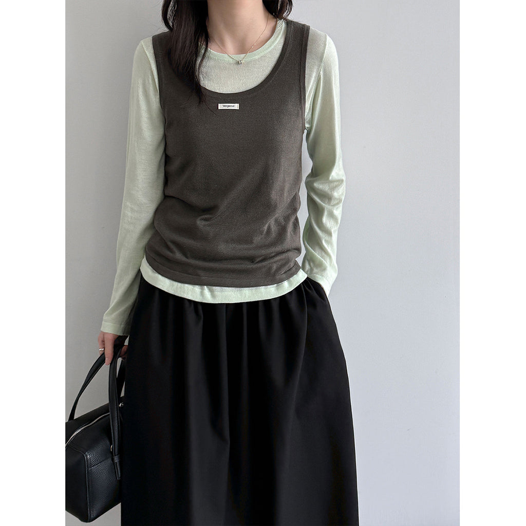 Model wearing a dark camisole over a pale long-sleeve top