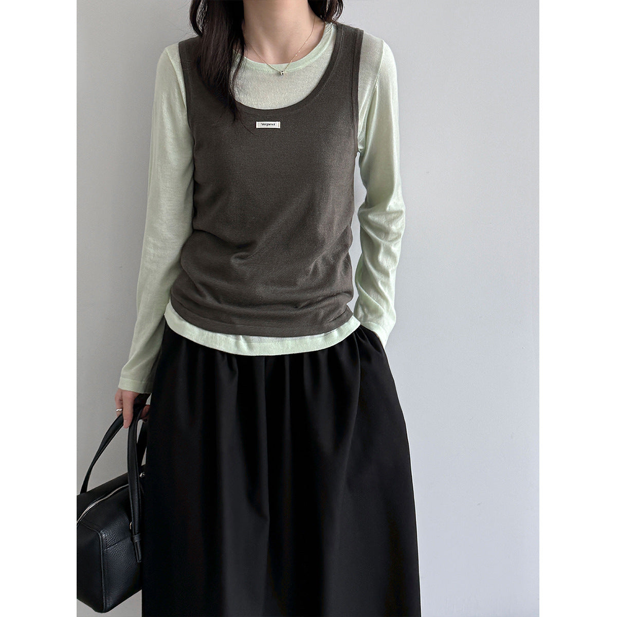 Model wearing a dark camisole over a pale long-sleeve top