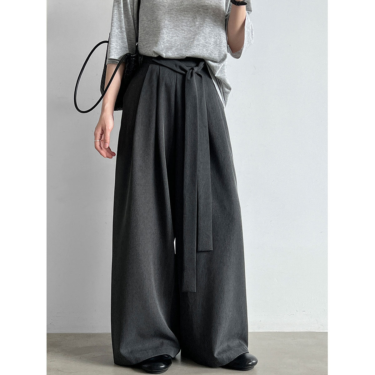 Model wearing dark belted wide-leg trousers