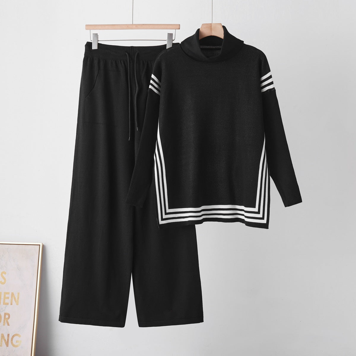 Black knit sweater and matching trousers on hangers