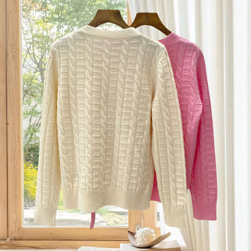 Cream cable-knit pullover with other colors behind